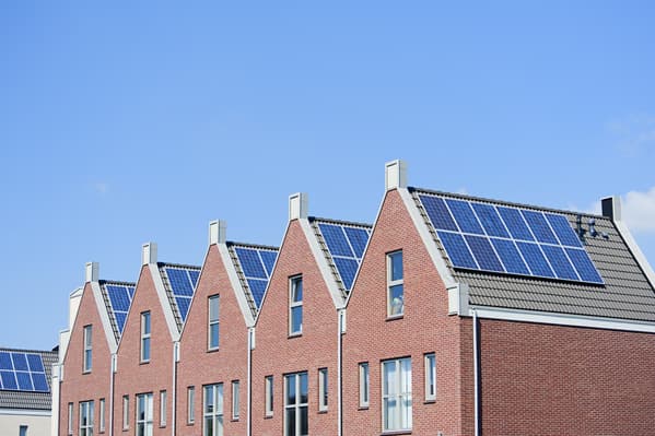 Rij nieuwbouwwoningen met zonnepanelen op de dakvlakken